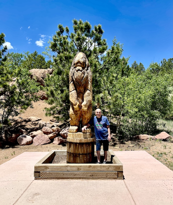 Steve standing next to a wood sculpture of Big Foot at Pikes Peak in Colorado