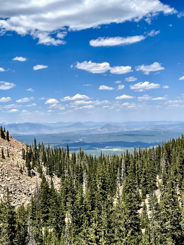 Mountains sprawling below plateau with trees as we drive up Pikes Peak in Colorado