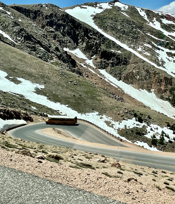 Yellow school bus on hairpin turn going up Pikes Peak in Colorado