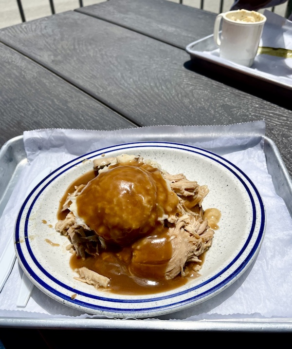 Blue rimmed white plate topped with slices of turkey alongside a scoop of mashed potatoes topped with brown gravy