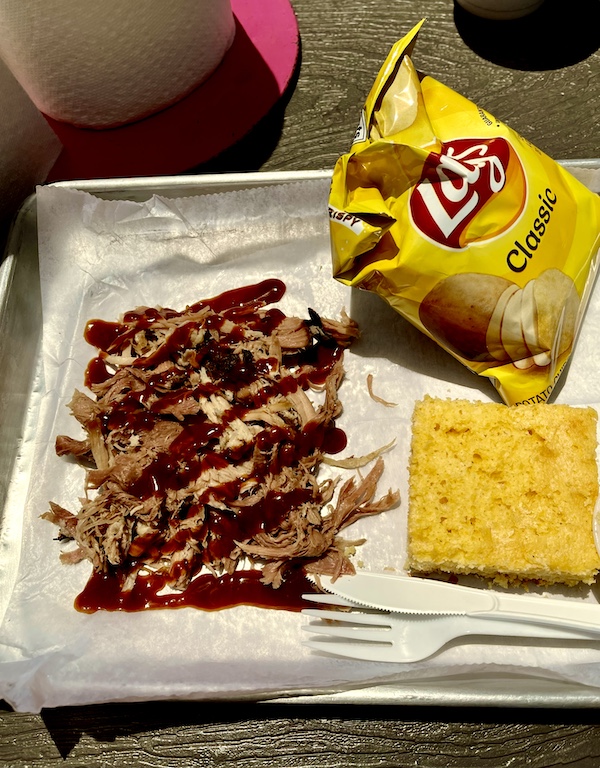 Small sheet pan topped with pulled pork a square of corn bread and a bag of Lays chips at Thee Pitts Again BBQ