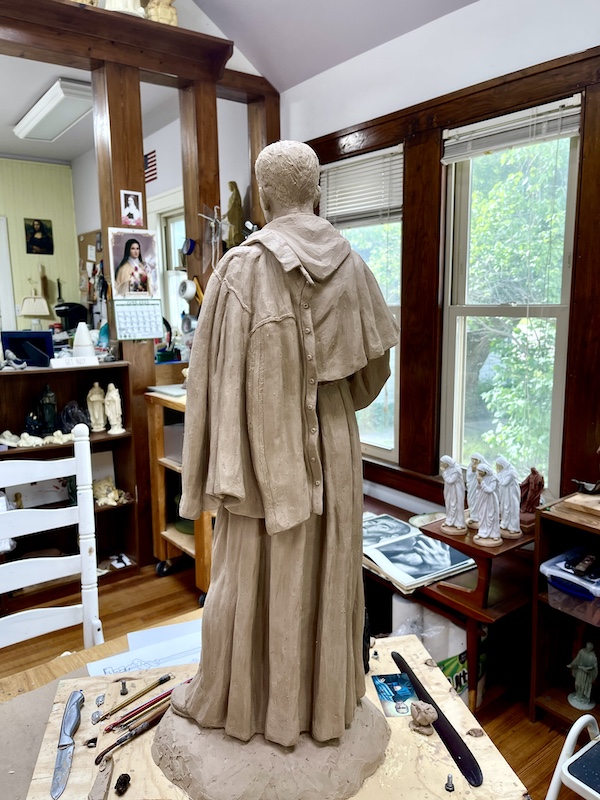Rear view of clay statue of a priest in Sondra Jonson's studio