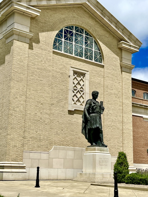 Tan brick church with bronze statue of an architect seen during our Fun Time at Notre Dame