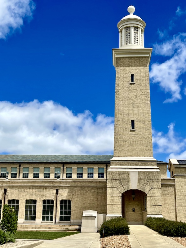 Church tower rises above tan brick building seen on our Fun Time at Notre Dame