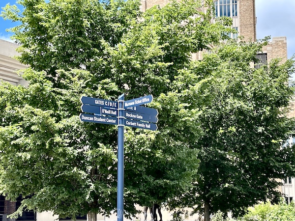 Blue post with directional signs in front of trees part of our Fun Time at Notre Dame