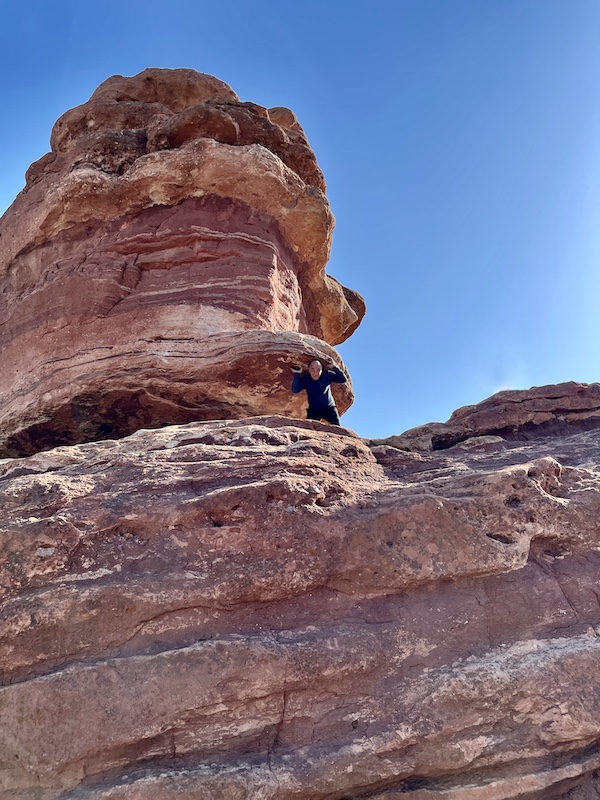 Steve high up on Balanced Rock pretending to be holding it up at Garden of the Gods