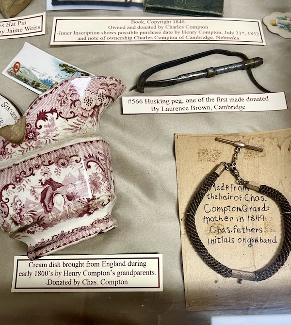 Display case showing maroon and white pitcher, hair bracelet and other artifacts at Nebraska's Cambridge Museum