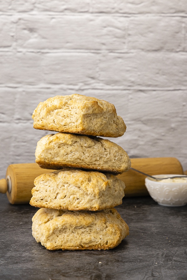 Stack of biscuits on black surface with dish of cream cheese and spreader from 30 Breads to Bake Before You Die