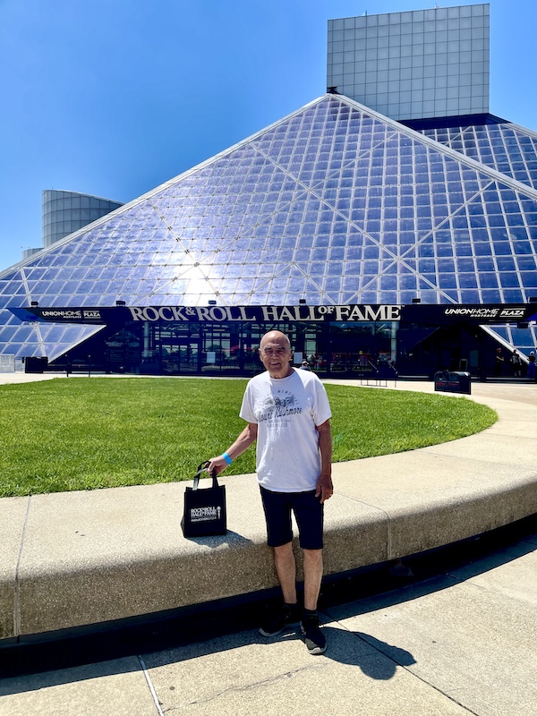 Steve standing by grassy area in front of the glass wall of the Rock and Roll Hall of Fame