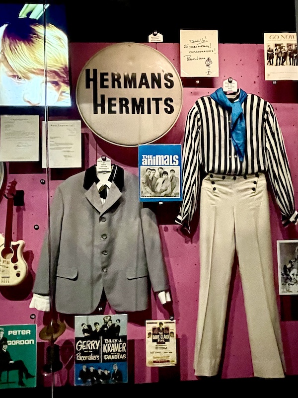 Striped shirt, beige pants and gray jacket worn by Herman's Hermits