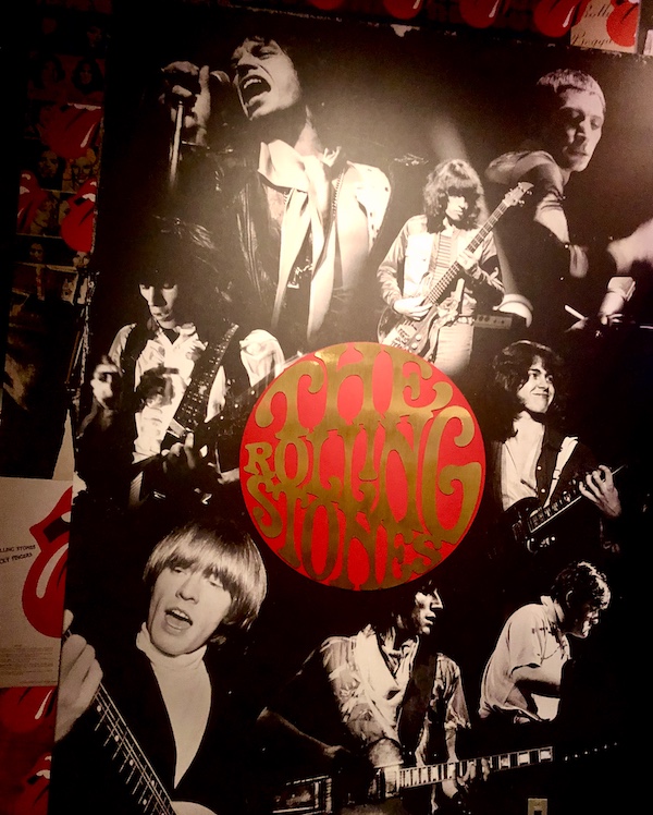Black and white poster of musicians with red circle with gold letters that read The Rolling Stones