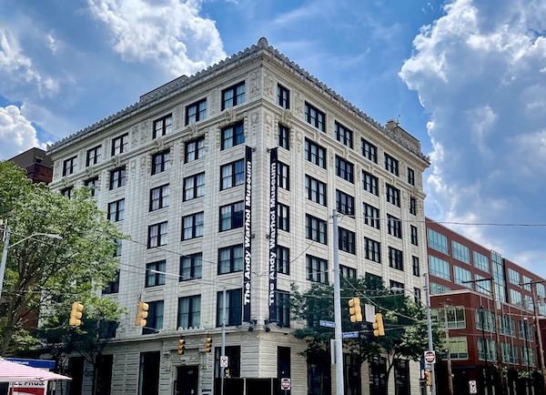 Gray multi-story building that houses the Andy Warhol Museum Pittsburgh on a street corner