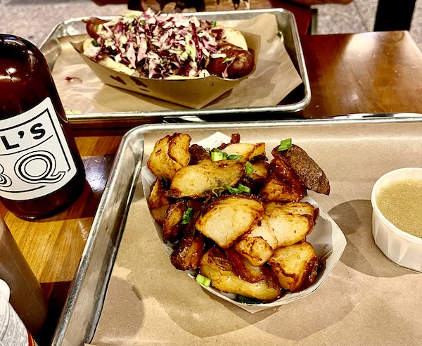 Dish of fried potatoes on a sheet pan with brown paper in foreground at Michael Symon's Mabel's BBQ