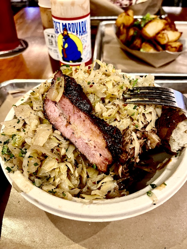 Plate of cabbage and other meats with meaty spare rib on top at Michael Symon's Mabel's BBQ