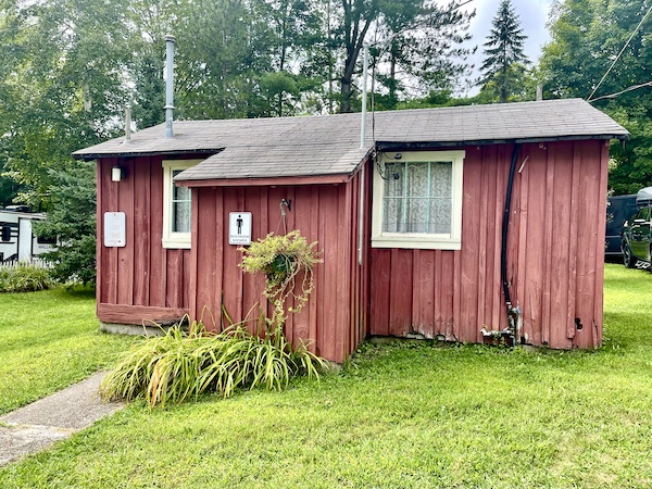 Red painted wood building with white trimmed windows and lawn at our campground in Upstate New York