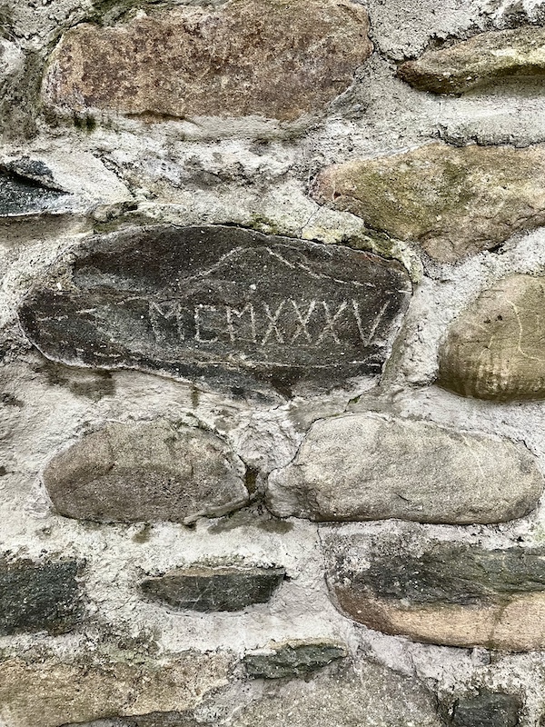 Stone wall of fireplace with MCMXXXV etched on one stone in Upstate New York