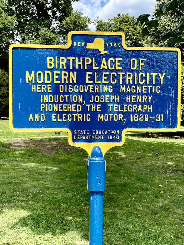Blue and yellow sign designating the site of the birthplace of modern electricity in Upstate New York