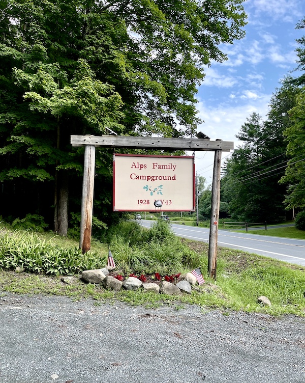 Welcome sign, lawn, trees and road to Alps Family Campground in Upstate New York