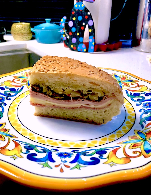 Colorful plate with a quarter of a large round deli sandwich to Welcome Back Central Grocery NOLA
