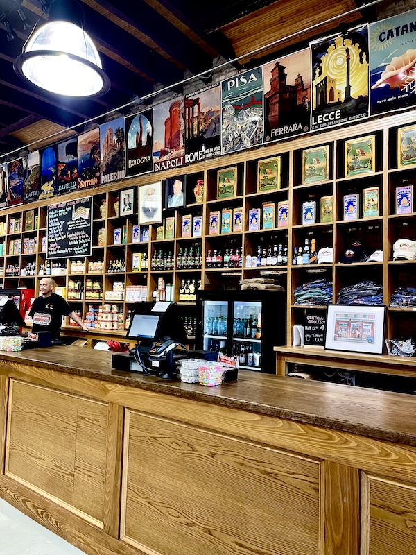 Cubicles holding bottles and jars behind counter to Welcome Back Central Grocery NOLA