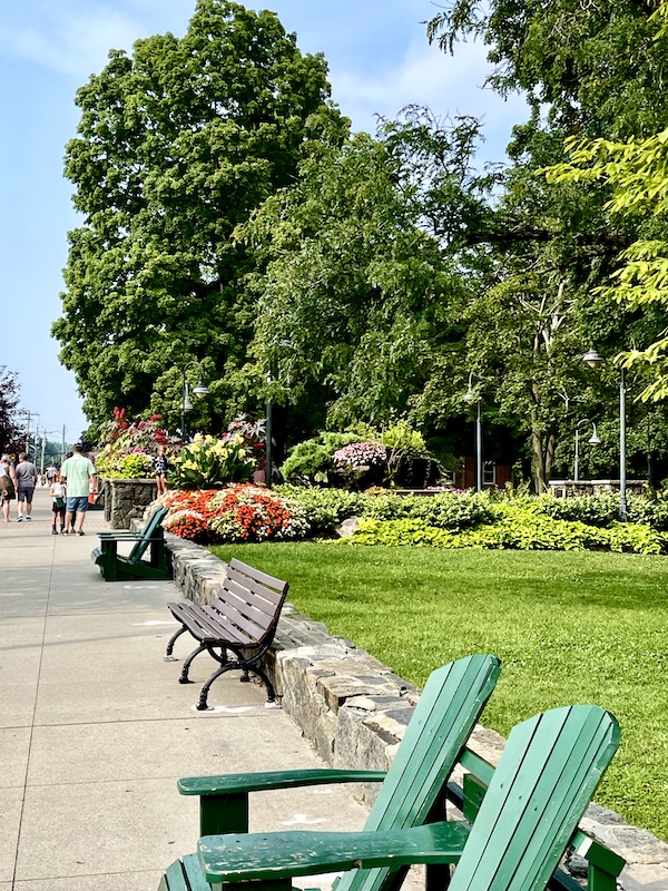 Path by the park with benches and green Adirondack chairs at Lake George New York