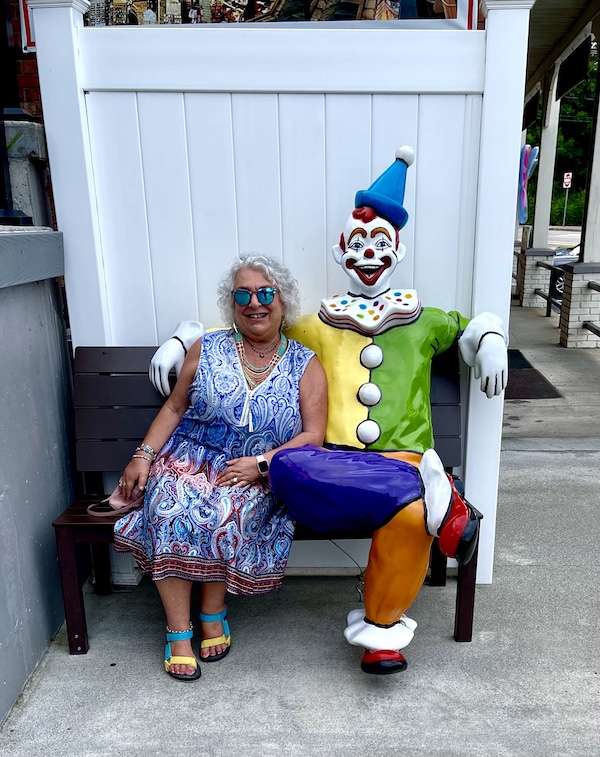 Me sitting with a colorful clown sculpture on a bench in Lake George New York