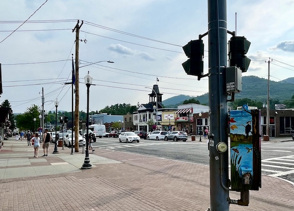 Red pavered sidewalk, traffic lights and shops across the street in Lake George New York