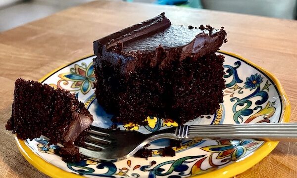 A square of My Bubie's very dark Chocolate Cake on a colorful plate with a forkful ready for my mouth.