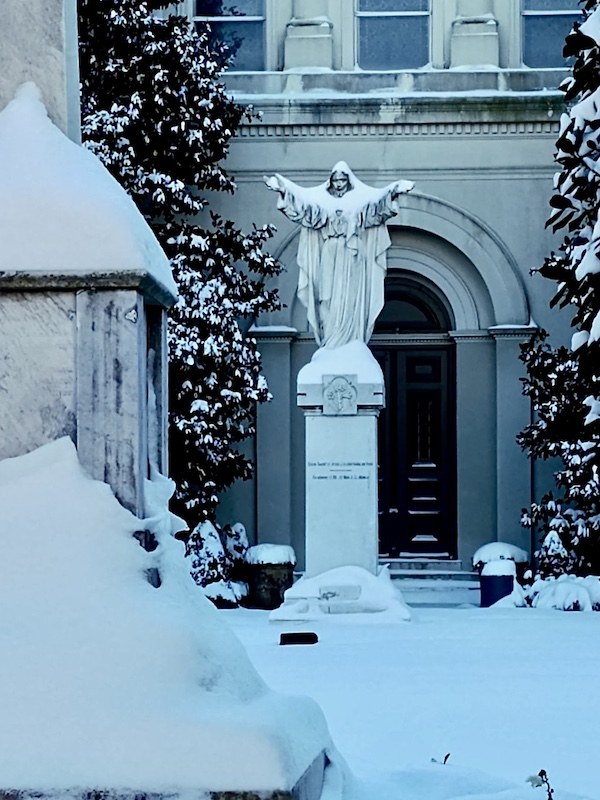 NOLA Should be Renamed SNOWLA! Religious statue covered in snow in front of a church.