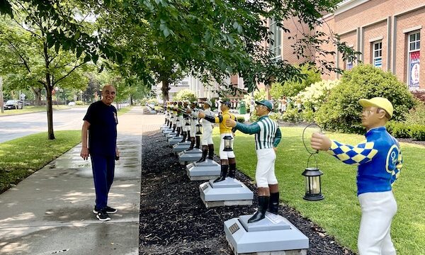 Steve on the sidewalk next to a row of colorful lawn jockeys at the National Museum of Racing and Hall of Fame
