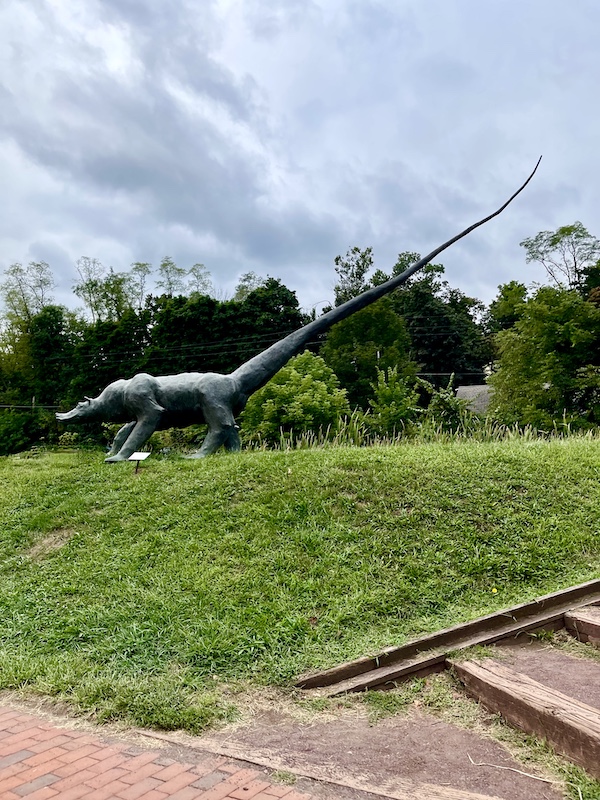 Bronze sculpture of a dinosaur on a lawn seen after visiting the Sand Sculptures Peddler's Village