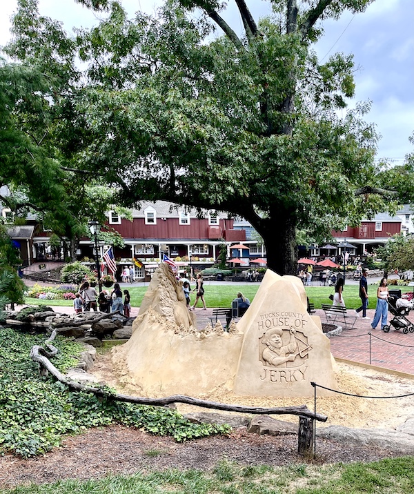 One of the Sand Sculptures Peddler's Village looks like mountain peaks and from the rear a man is carved, banging a triangle, in a window