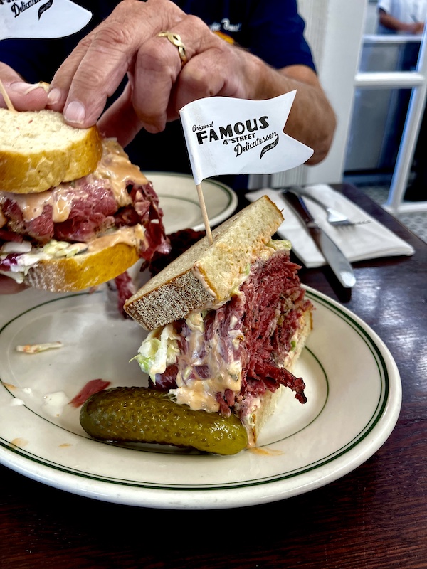 Deli meat sandwich on rye bread with coleslaw and Russian Dressing on a plate at Famous 4th Street Deli.