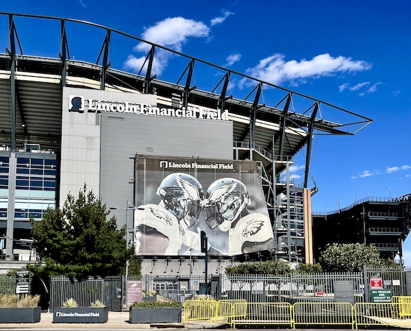 Pair of football players, helmet to helmet with Eagles logos on back of stands at stadium seen on Tour of Downtown Philadelphia
