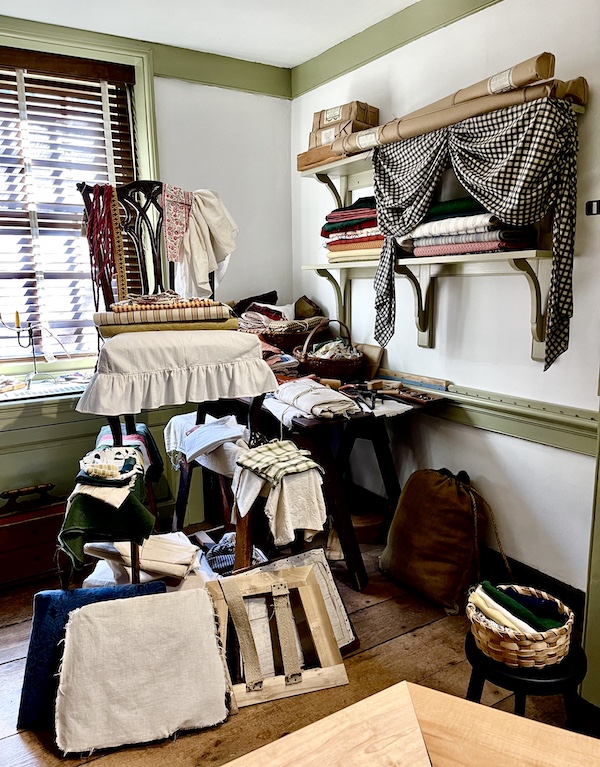 Chair being upholstered, shelf on wall and assorted fabric seen at Betsy Ross' House.