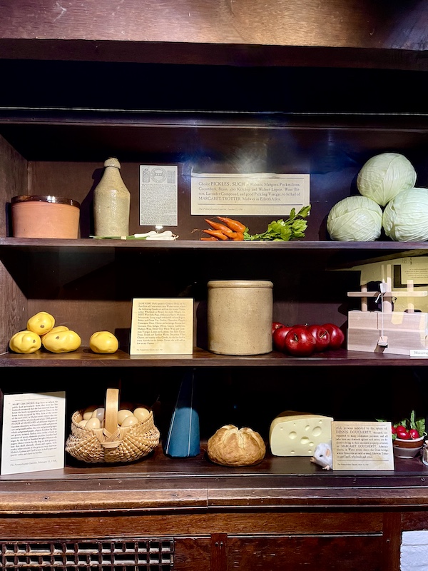 Wood shelfs with fake fruit and veggies on display at Betsy Ross' house.