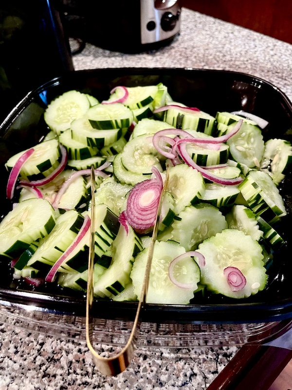 Sliced cucumbers and red onion in a black salad dish we enjoyed this Autumn.