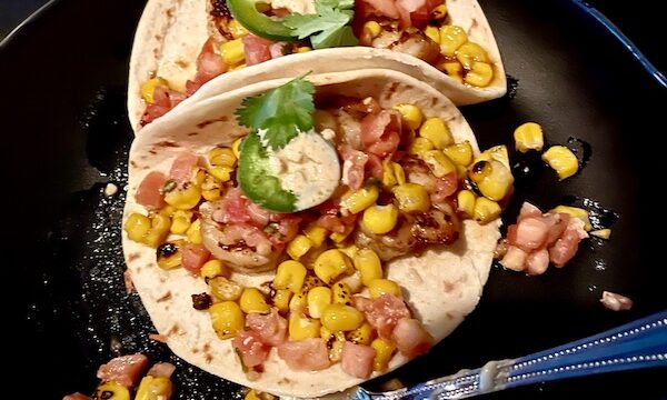Pair of shrimp filled tacos on a black plate with a fork across the front edge at Basket lined with deli paper and filled with seasoned crinkle fries at Chickie's and Pete's Atlantic City