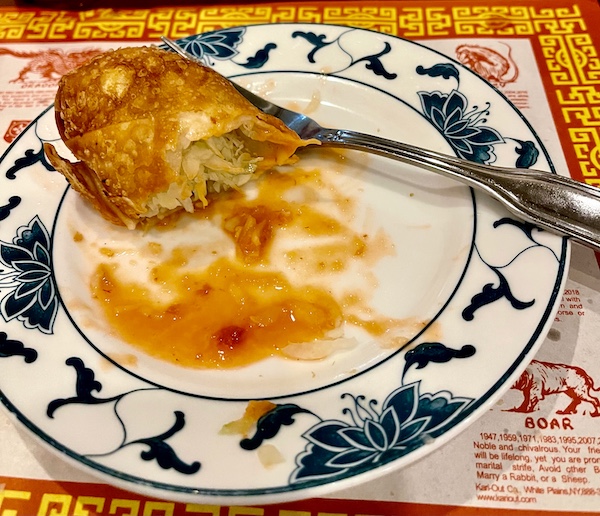 White and blue plate topped with orange colored sauce, a fork and a partially eaten egg roll from China Sea of Absecon NJ