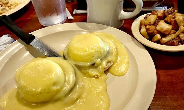 Beige plate topped with two poached eggs covered with lots of Hollandaise sauce and mug of coffee. At Jimmy's Family Restaurant Easley SC this also came with a dish of diced hash browns.