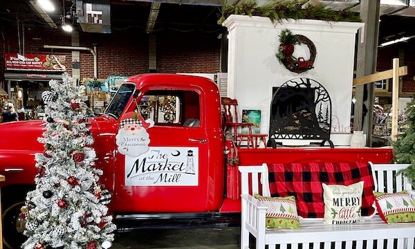 Red pickup truck with white Christmas tree and white bench at The Market at the Mill Pickens SC