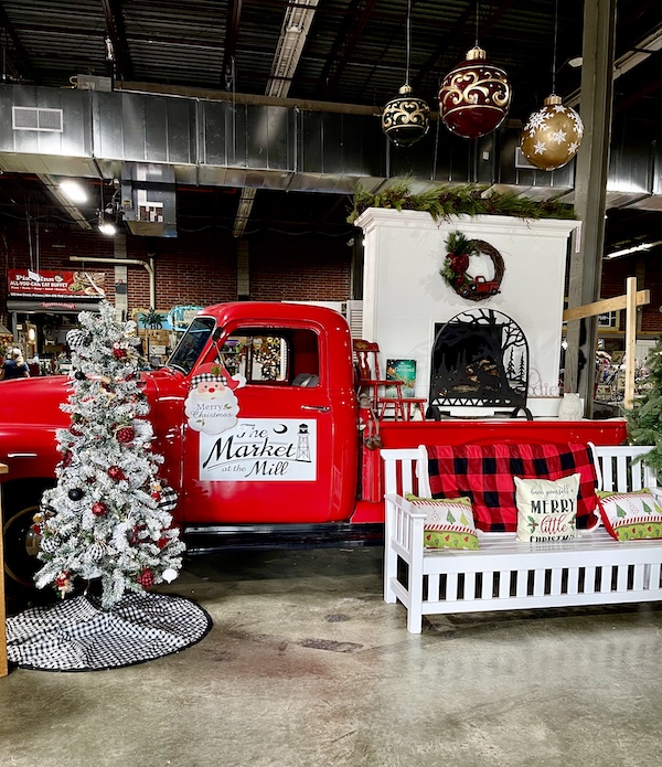Red pickup truck with white Christmas tree and white bench at The Market at the Mill Pickens SC