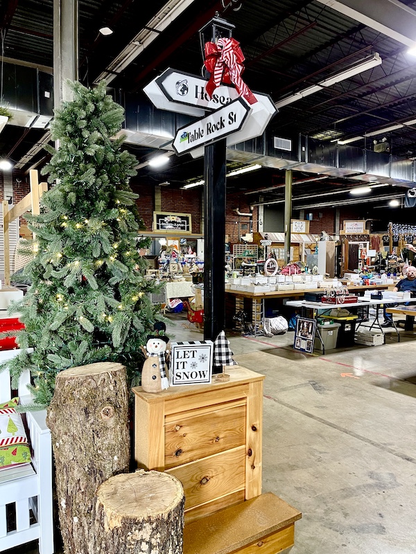 Flea market items on display, Christmas tree and street sign at The Market at the Mill Pickens SC