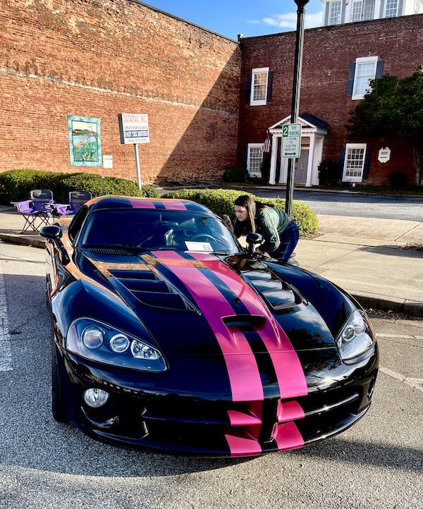 Black sports car with bright pink racing stripes at the Downtown Pickens Car Show