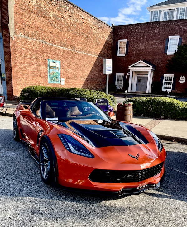 Newish metallic orange Corvette with black on hood at the Downtown Pickens Car Show
