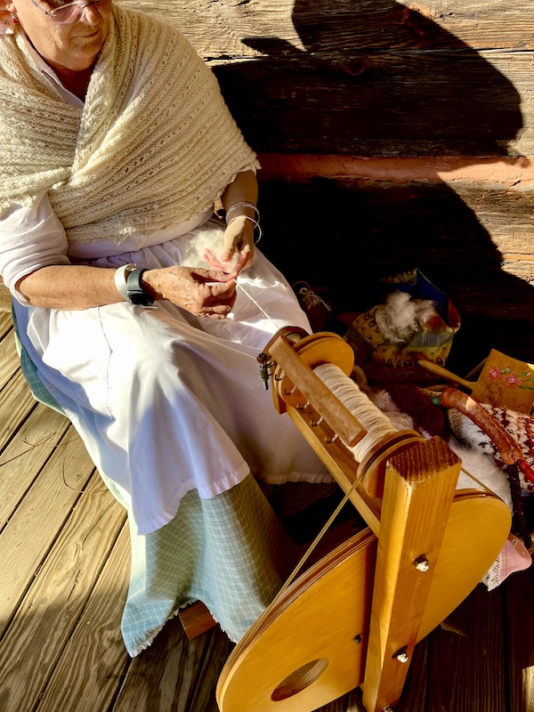 Woman in Colonial attire working a spinning wheel to make yarn at the Hagood Mill Native American Celebration