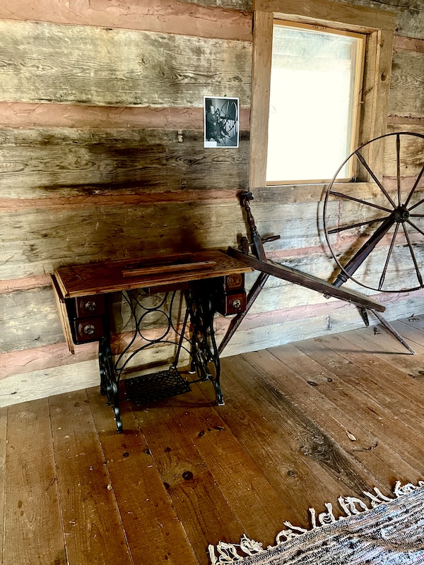 Antique sewing machine table and spinning wheel in a log room at Hagood Mill Native American Celebration