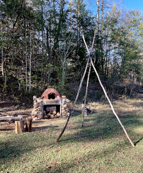 Frame for a teepee on the lawn alon with a wood burning oven and trees at Hagood Mill Native American Celebration