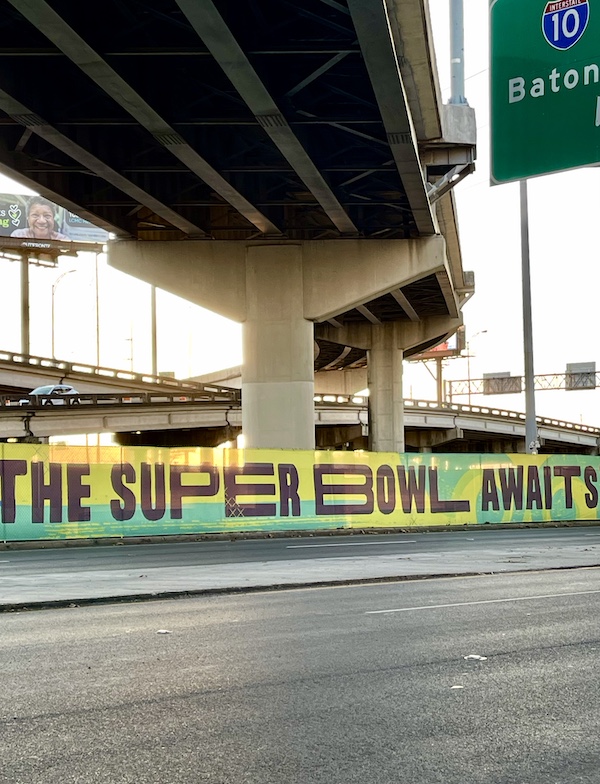 Green and yellow banner on a wall under the highway Celebrating Super Bowl NOLA Style
