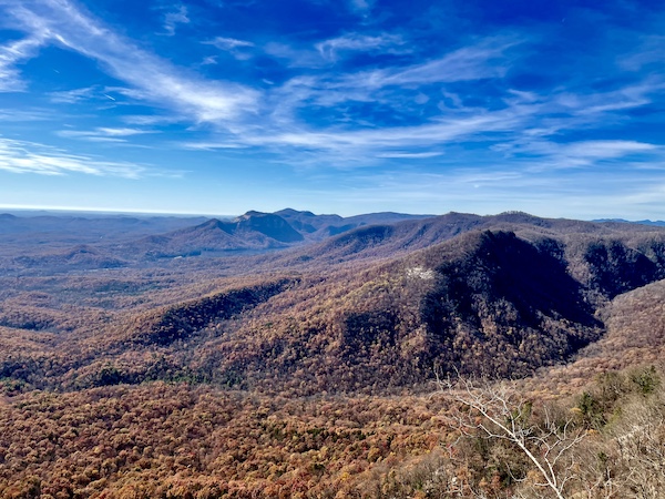 Mountains and valleys covered in trees with multicolored leaves and blue sky. Happily Back to Writing!